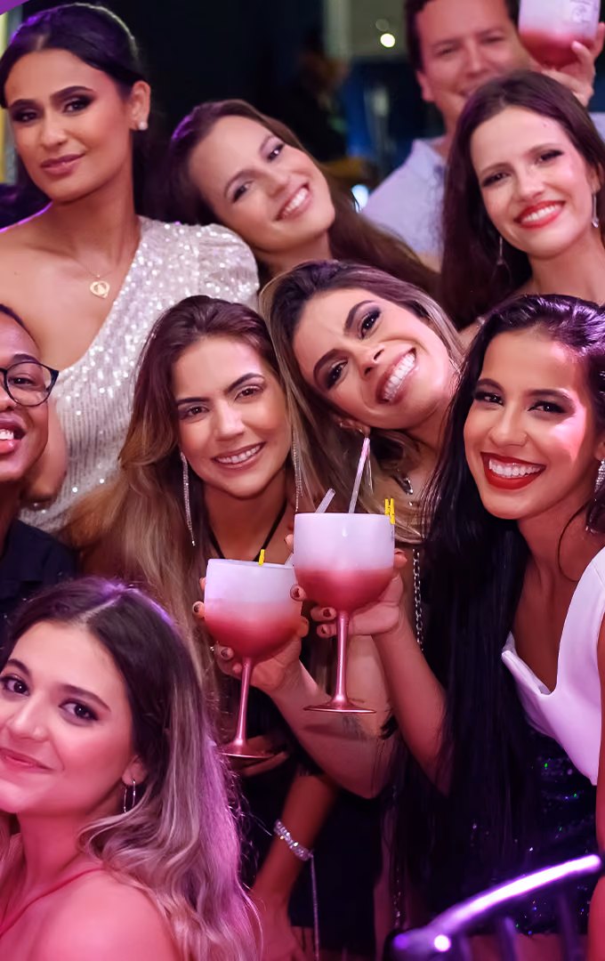 Grupo de formandas e convidados brinda com taças no baile de gala unificado.